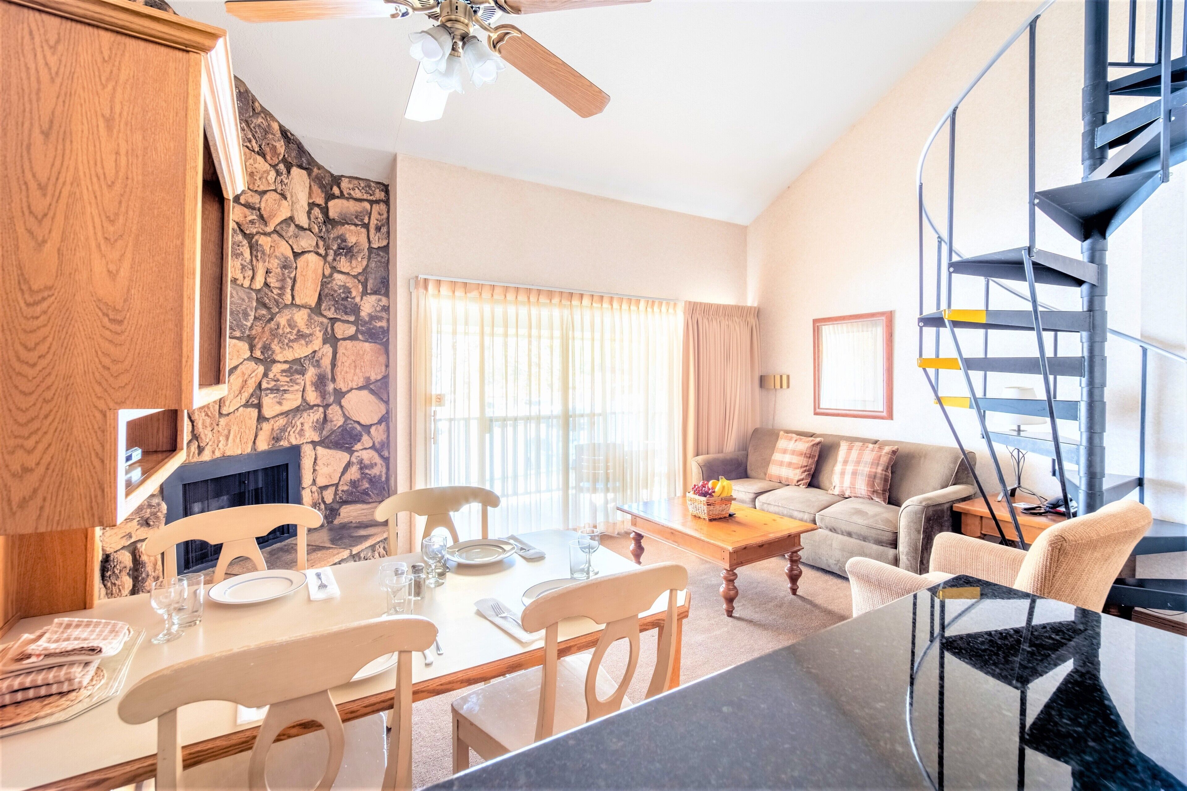 Un comedor con pared de piedra, chimenea y escalera.