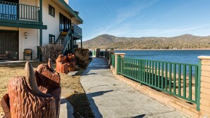 A waterfront property with a concrete walkway, a green railing, and a building with a balcony. - Lagonita Lodge (Big Bear Lake)
