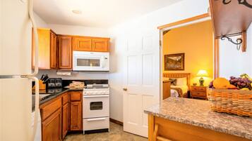 A kitchen with wooden cabinets, a white microwave, a stove, and a refrigerator.