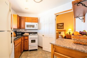 A kitchen with wooden cabinets, a white microwave, a stove, and a refrigerator.