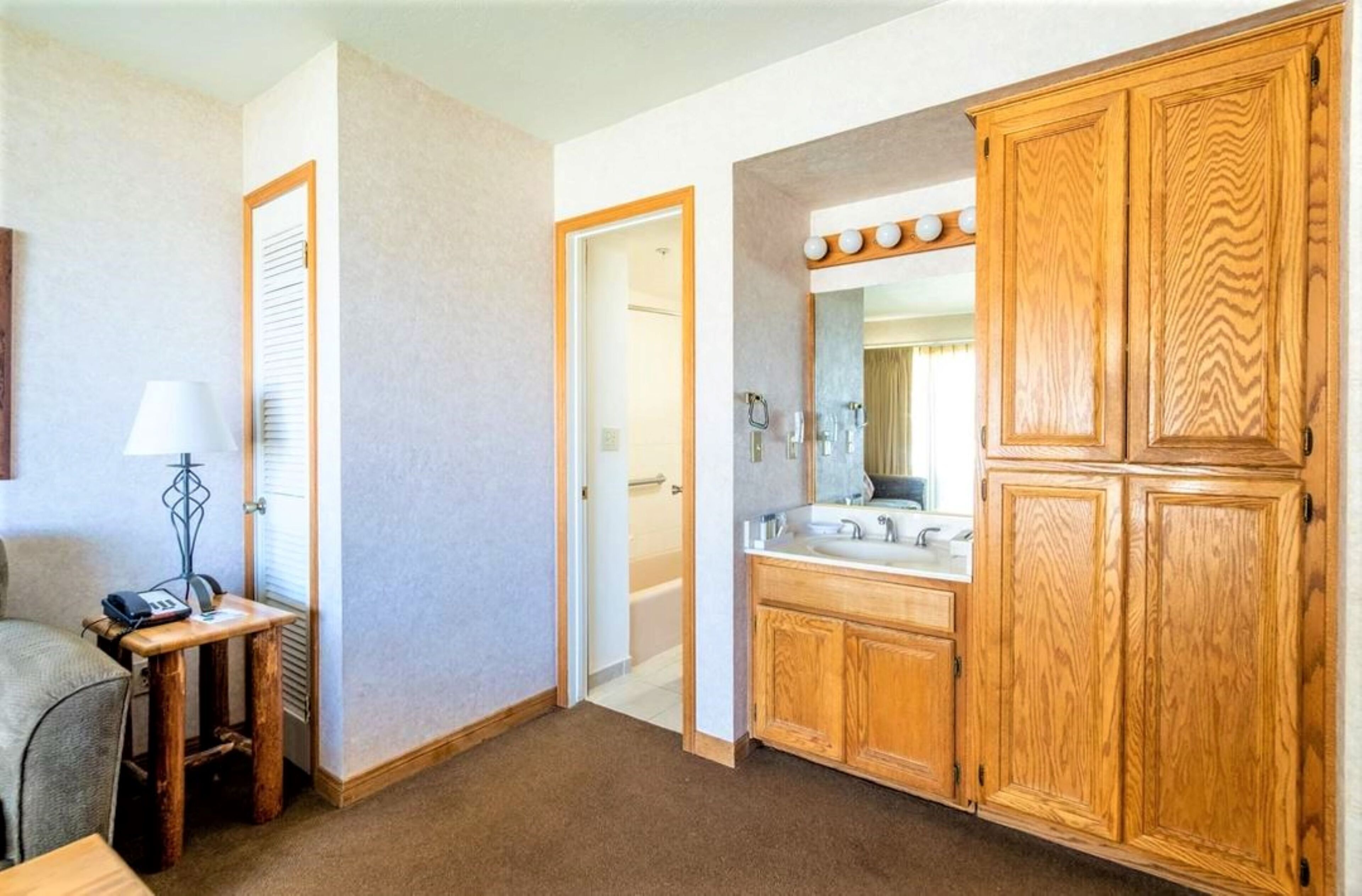 Un bagno d'hotel con armadietti in legno, un mobile lavabo con specchio e uno spazio doccia.
