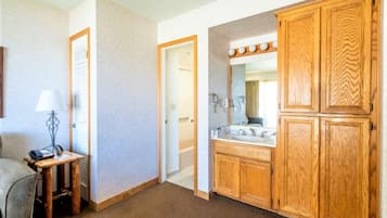Un bagno d'hotel con armadietti in legno, un mobile lavabo con specchio e uno spazio doccia.