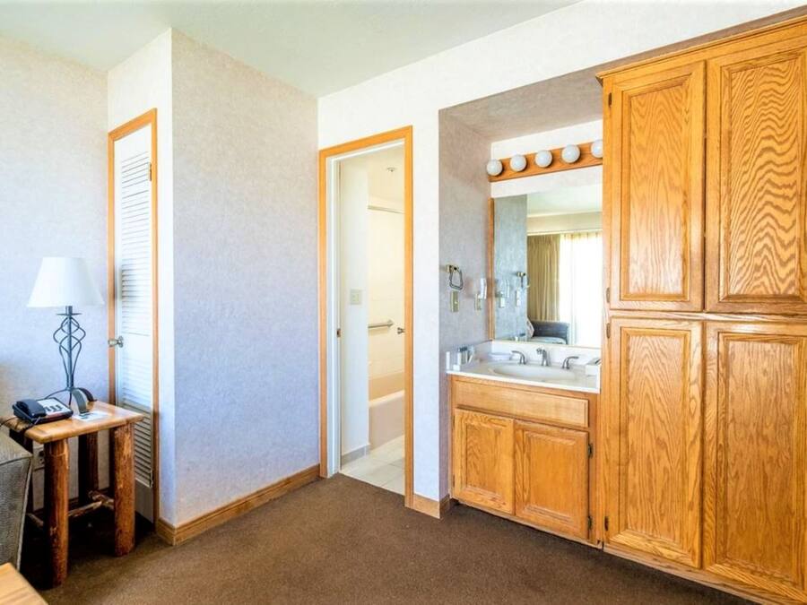 Un bagno d'hotel con armadietti in legno, un mobile lavabo con specchio e uno spazio doccia.
