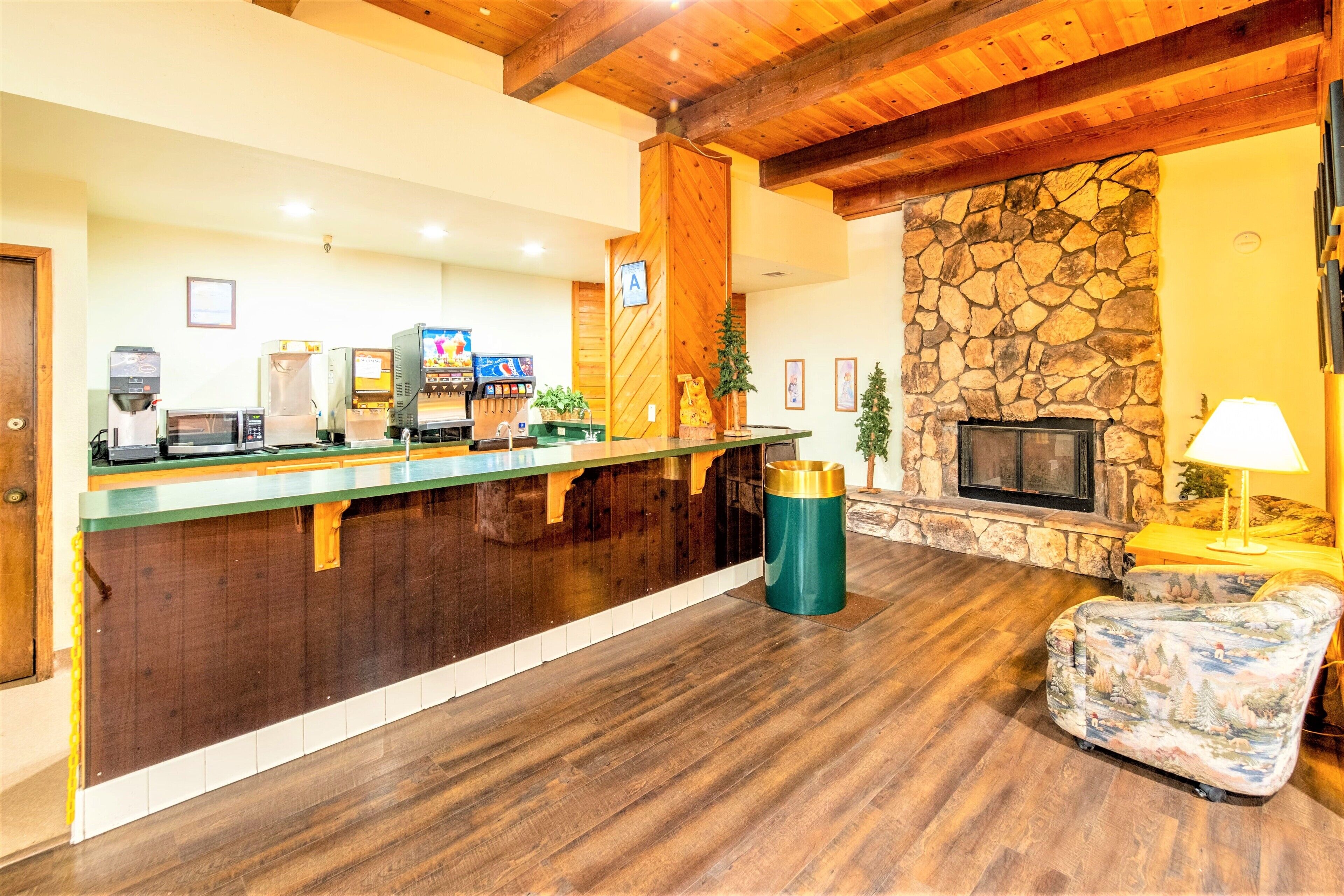 A reception area with a wooden counter, coffee machines, a stone fireplace, and a cozy seating area.