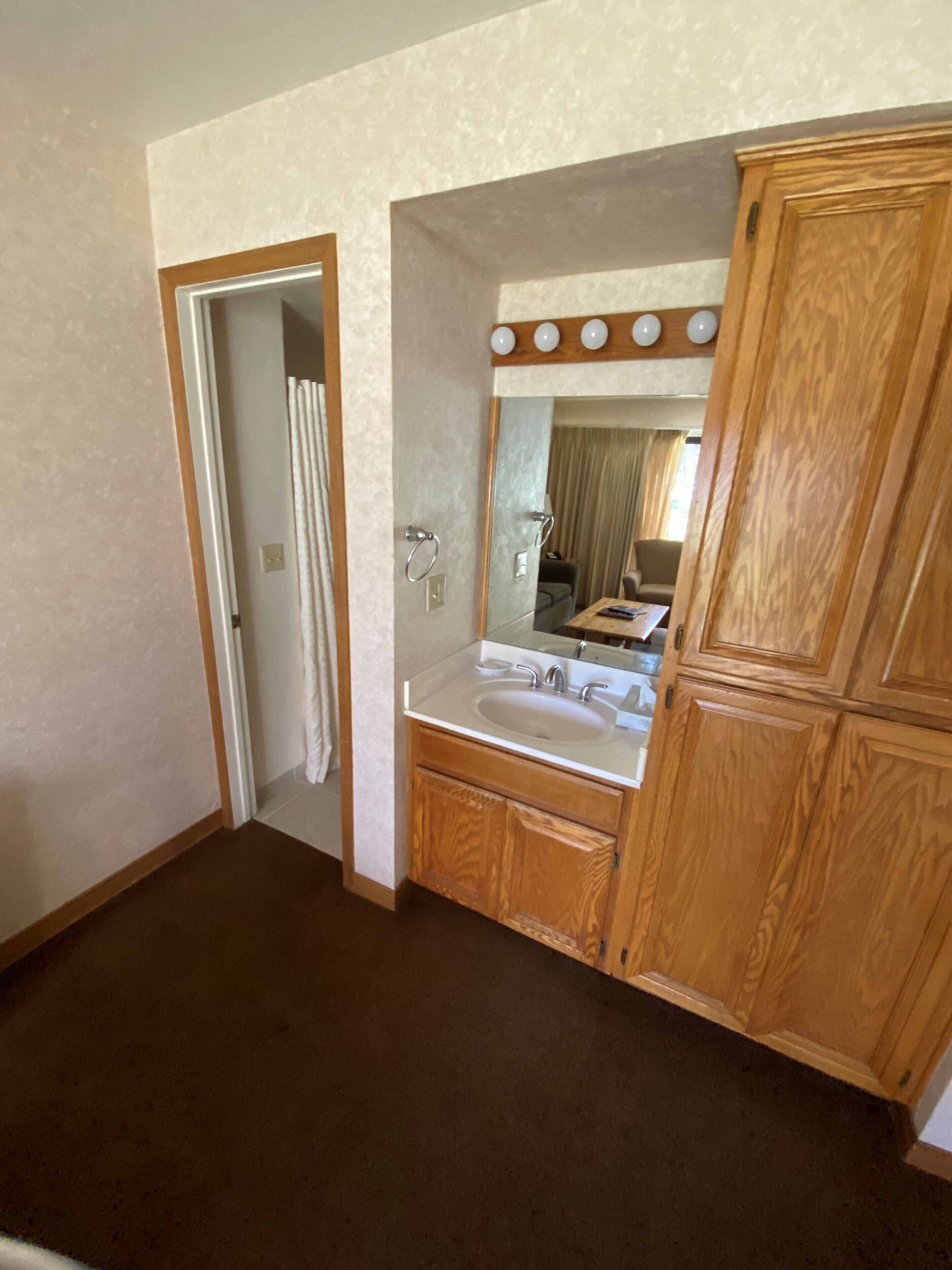 A bathroom with a wooden vanity, a sink, and a mirror.