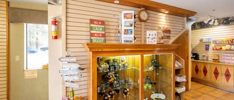 A cozy lodge with a glass display case filled with souvenirs, a wooden signpost with directional signs, and a fire extinguisher mounted on the wall.