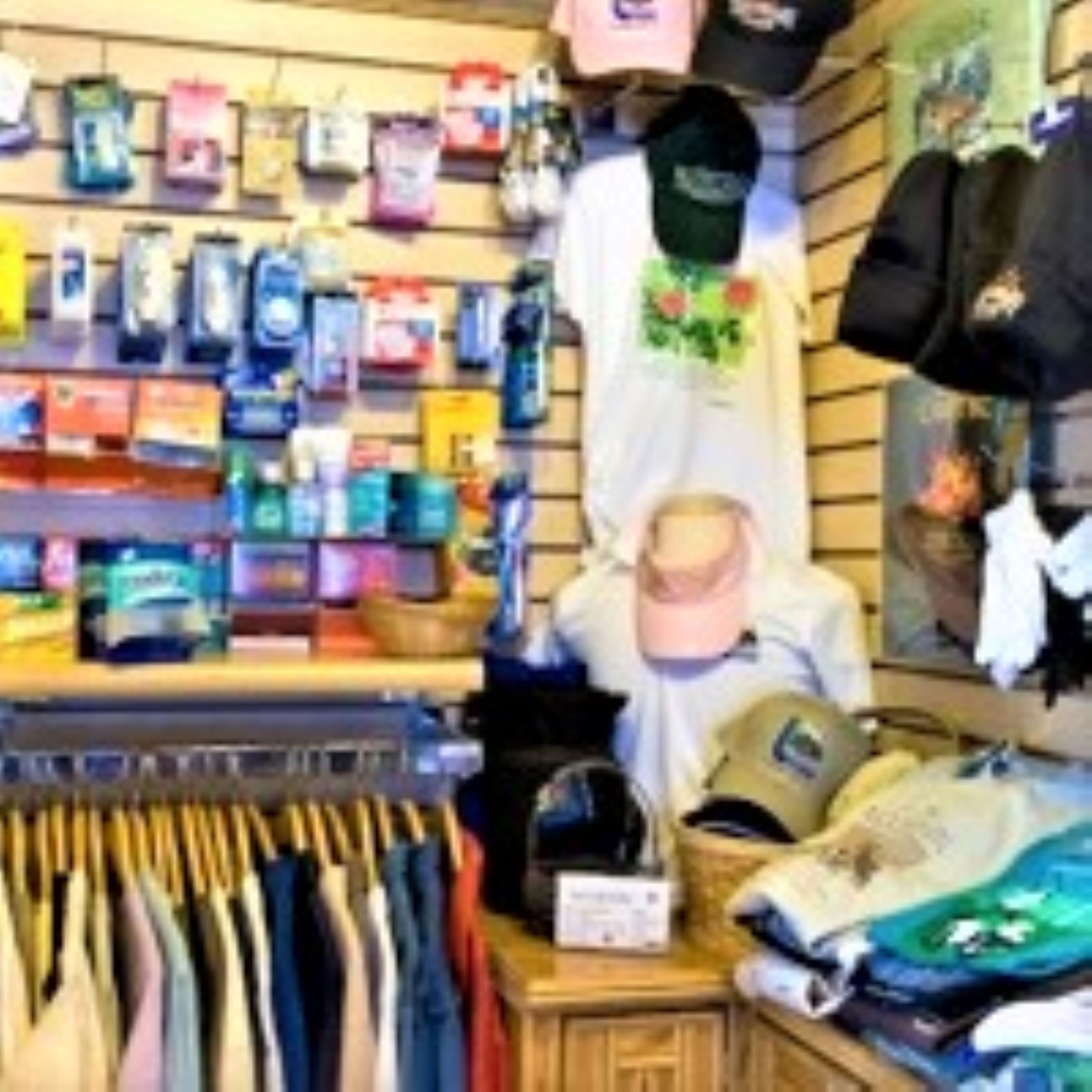 Una tienda de ropa con diversos artículos expuestos, incluyendo sombreros, camisetas y un maniquí.