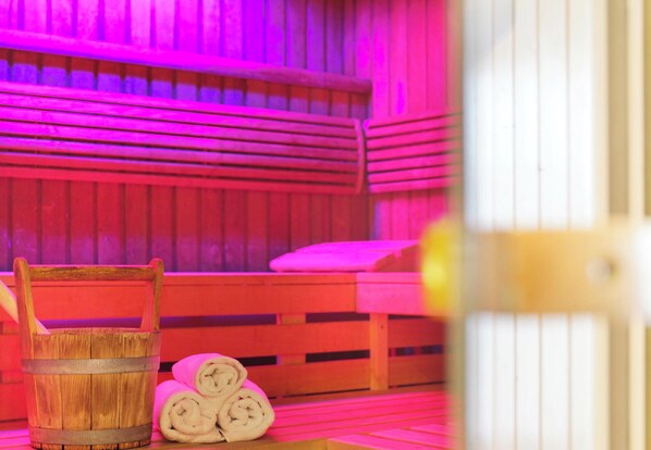 A sauna room with wooden benches and a wooden bucket. - Best Western Macrander Hotel Dresden (Dresden)