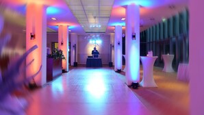 A hotel corridor with a reception desk, a stage with a podium, and tables with chairs. - Best Western Macrander Hotel Dresden (Dresden)