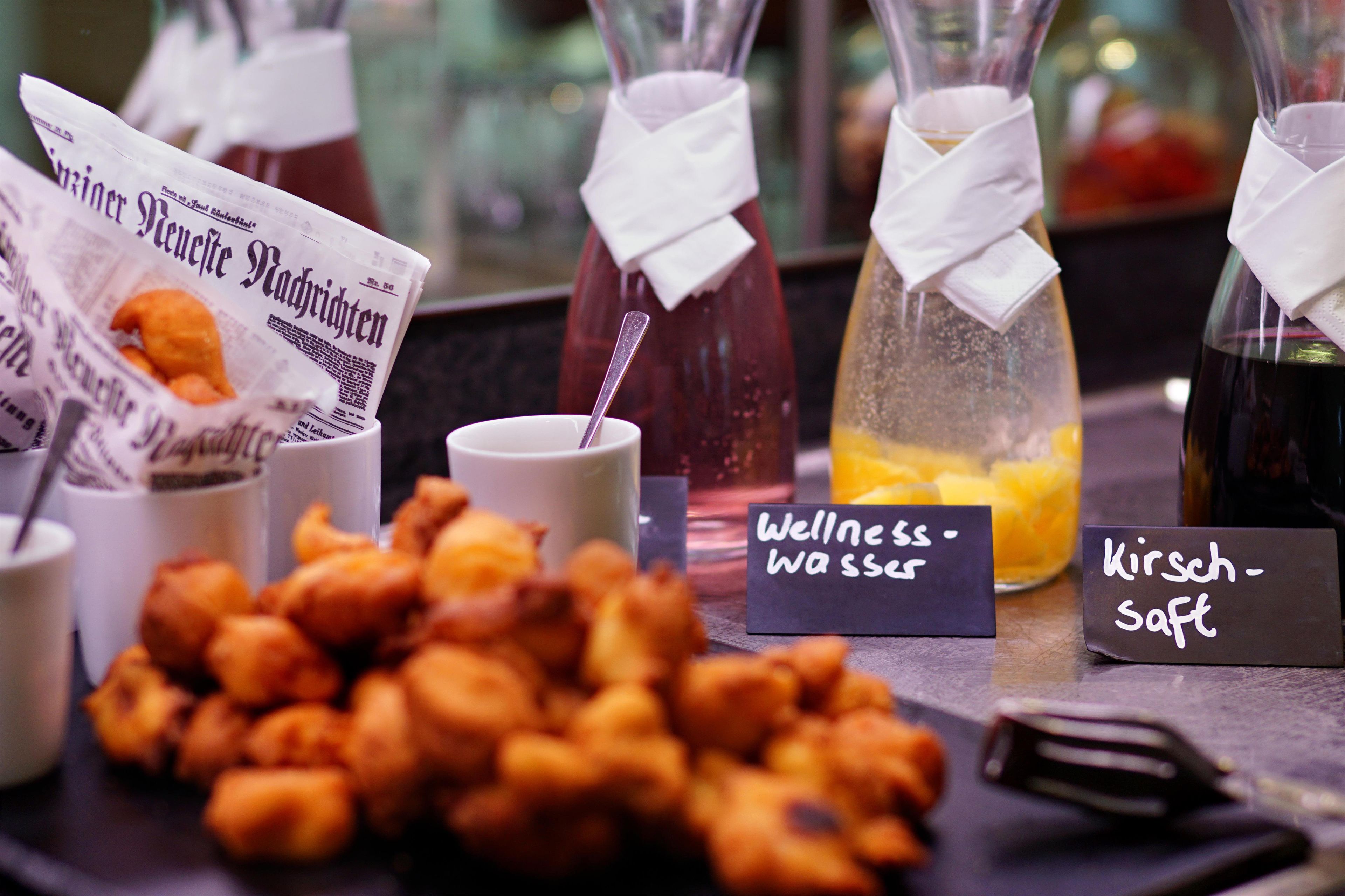 A selection of food items and beverages, including fried snacks, a newspaper, and labeled drink options.