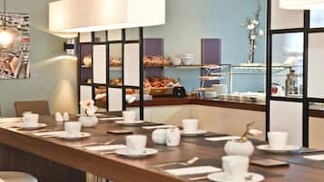 A conference room with a long table set for a meeting, a cityscape artwork on the wall, and a buffet area in the background.