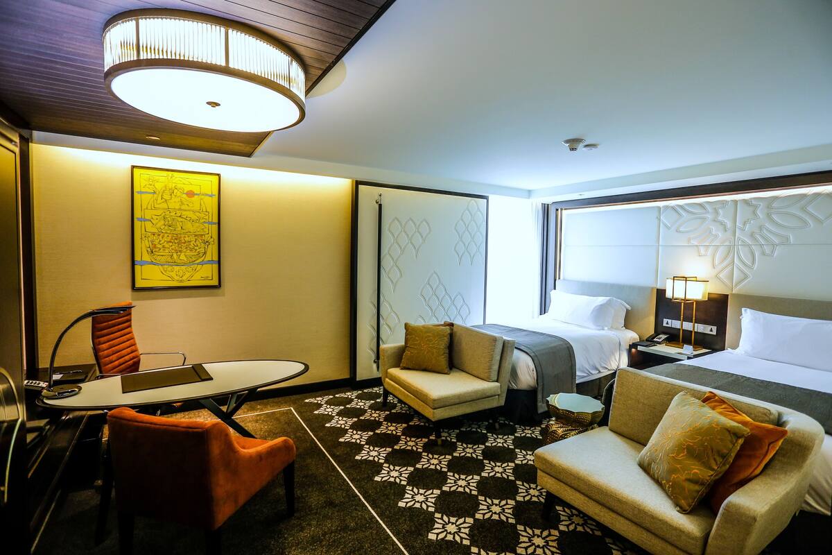 A hotel room with a bed, two sofas, a dining table, and a small desk.