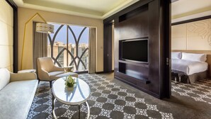 A hotel room with a sofa, armchair, round coffee table, TV, and a bed. - InterContinental Dhaka by IHG (Dhaka)