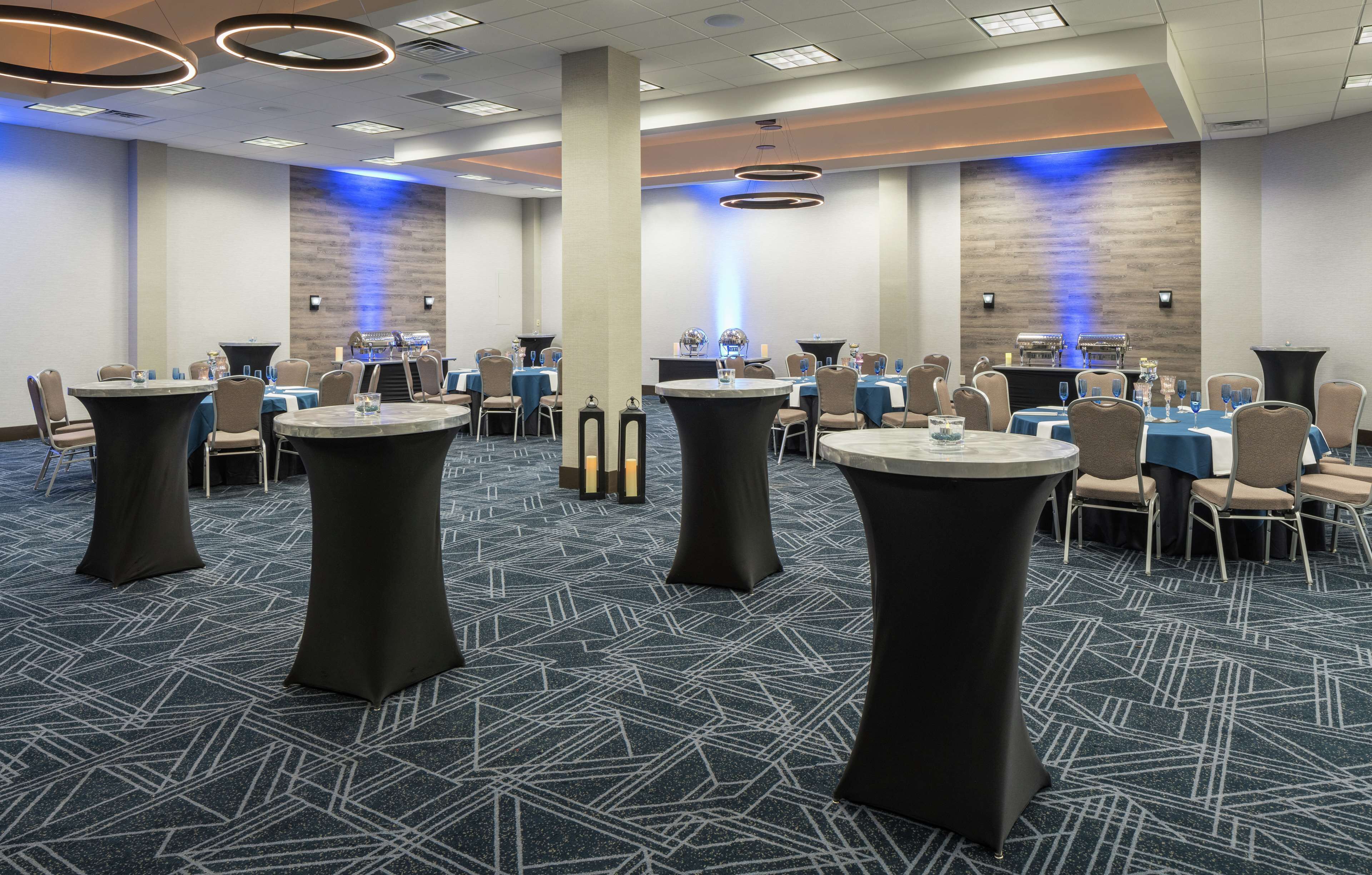 A conference room with round tables, chairs, and a stage with a podium.