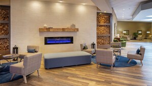 Um lobby moderno com lareira, área de estar e detalhes em madeira.