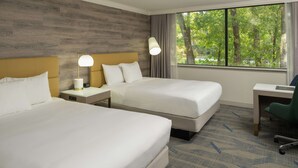 Quarto de hotel com duas camas, uma escrivaninha e uma cadeira.