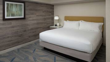 A hotel room with a large bed, a nightstand with a lamp, and a framed picture on the wall.
