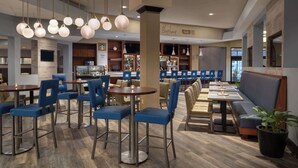 A modern restaurant with bar seating, a Starbucks sign, and a bar area with a counter and shelves. - Hilton Durham near Duke University (Durham)