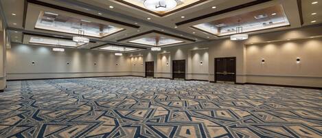 A large conference room with a patterned carpet, recessed lighting, and a central chandelier.