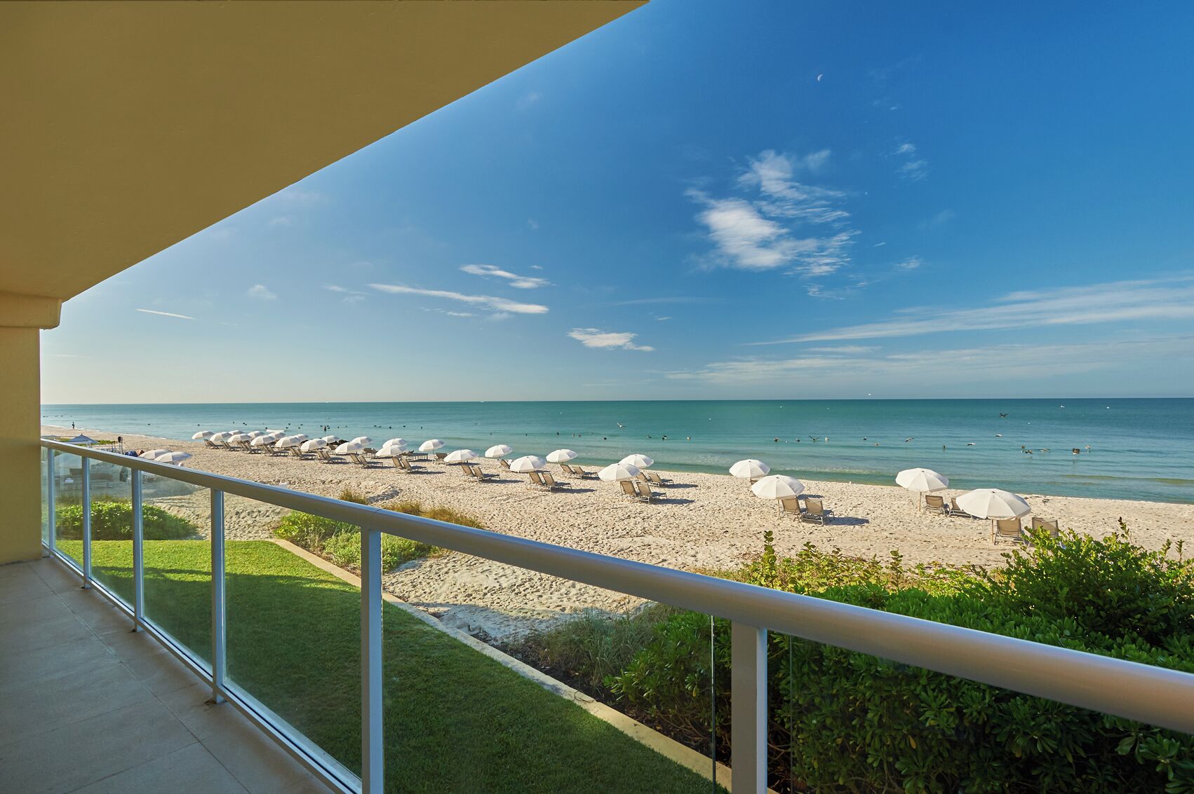 A balcony with a view of a beach with sun loungers and umbrellas.