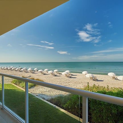 A balcony with a view of a beach with sun loungers and umbrellas.
