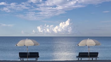 Relax in comfort under shaded lounge chairs, overlooking the calm sea.