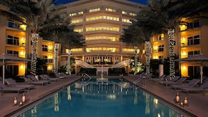 A hotel with a swimming pool, lounge chairs, and palm trees. - Edgewater Beach Hotel (Naples)