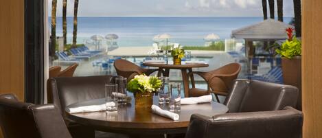 A dining area with a view of the beach and ocean.