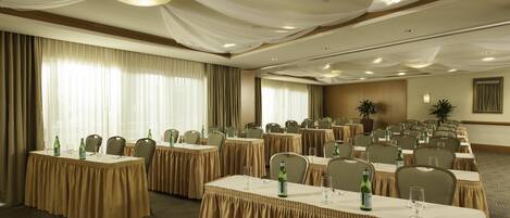 A conference room with multiple tables, chairs, and draped ceiling decorations.