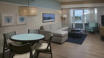 A modern living room with a sofa, dining table, chairs, and a TV.