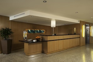 A modern reception desk with a wooden finish, a glass counter, and a potted plant.