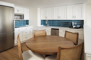 A modern kitchen with white cabinets, a stainless steel refrigerator, a microwave, and a coffee maker.