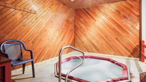 A wooden interior with a hot tub, a chair, and a wooden ceiling. - Super 8 by Wyndham Mackinaw City/Beachfront Area (Mackinaw City)
