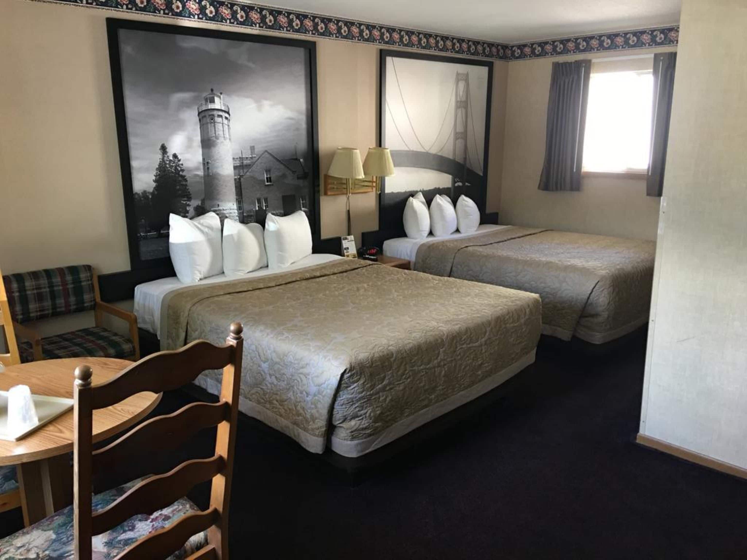 Ein Hotelzimmer mit zwei Betten, einem Schreibtisch, einem Stuhl und einer großen Wandmalerei.