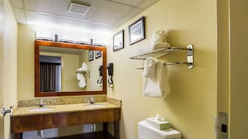 Un baño de hotel con lavamanos doble, inodoro, toallero y espejo.
