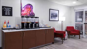 Un moderno vestíbulo de hotel con una estación de café, una fotografía enmarcadas de la ciudad y una silla roja.