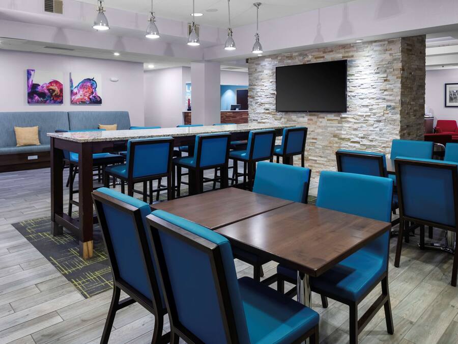 Un espace de détente moderne comprenant un bar, des coins salon et un téléviseur à écran plat fixé à un mur en pierre.