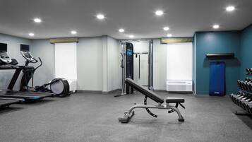 Una palestra con tapis roulant, panca piana, rack per squat e manubri.