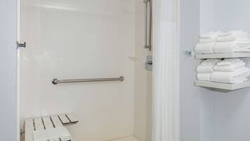 Un bagno con doccia, un porta asciugamani e uno scaffale con asciugamani piegati.