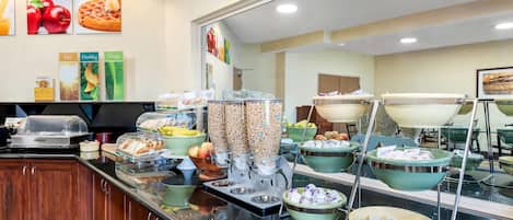 Zona de bufé con diversas opciones de comida, como waffles recién hechos, frutas y cereales.
