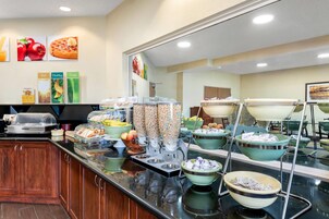 Zona de bufé con diversas opciones de comida, como waffles recién hechos, frutas y cereales.