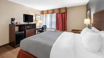Habitación de hotel con cama, escritorio con televisor, cafetera y microondas.