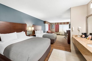 A hotel room with two beds, a desk, a chair, a bathroom, and a large mirror. - Quality Inn & Suites Lawrence - University Area (Lawrence)