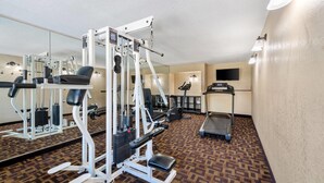 A gym with exercise equipment, a treadmill, and a patterned carpet.