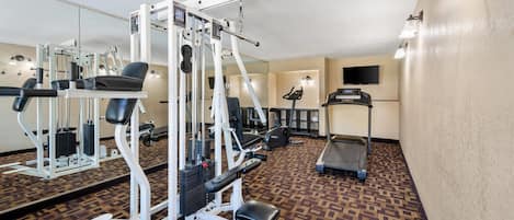 Un gimnasio con equipo de ejercicio, una cinta de correr y una alfombra estampada.