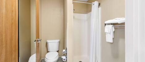 A bathroom with two toilets, a shower, and a towel rack.