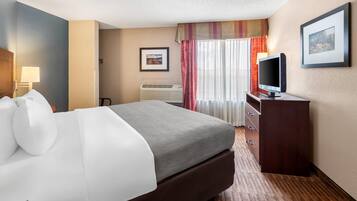 A hotel room with a bed, a television, a dresser, and a framed picture on the wall.