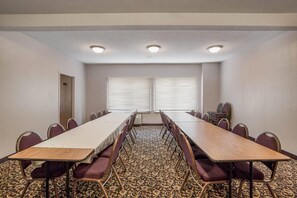A conference room with a long table, chairs, and two windows with blinds. - Quality Inn & Suites Lawrence - University Area (Lawrence)