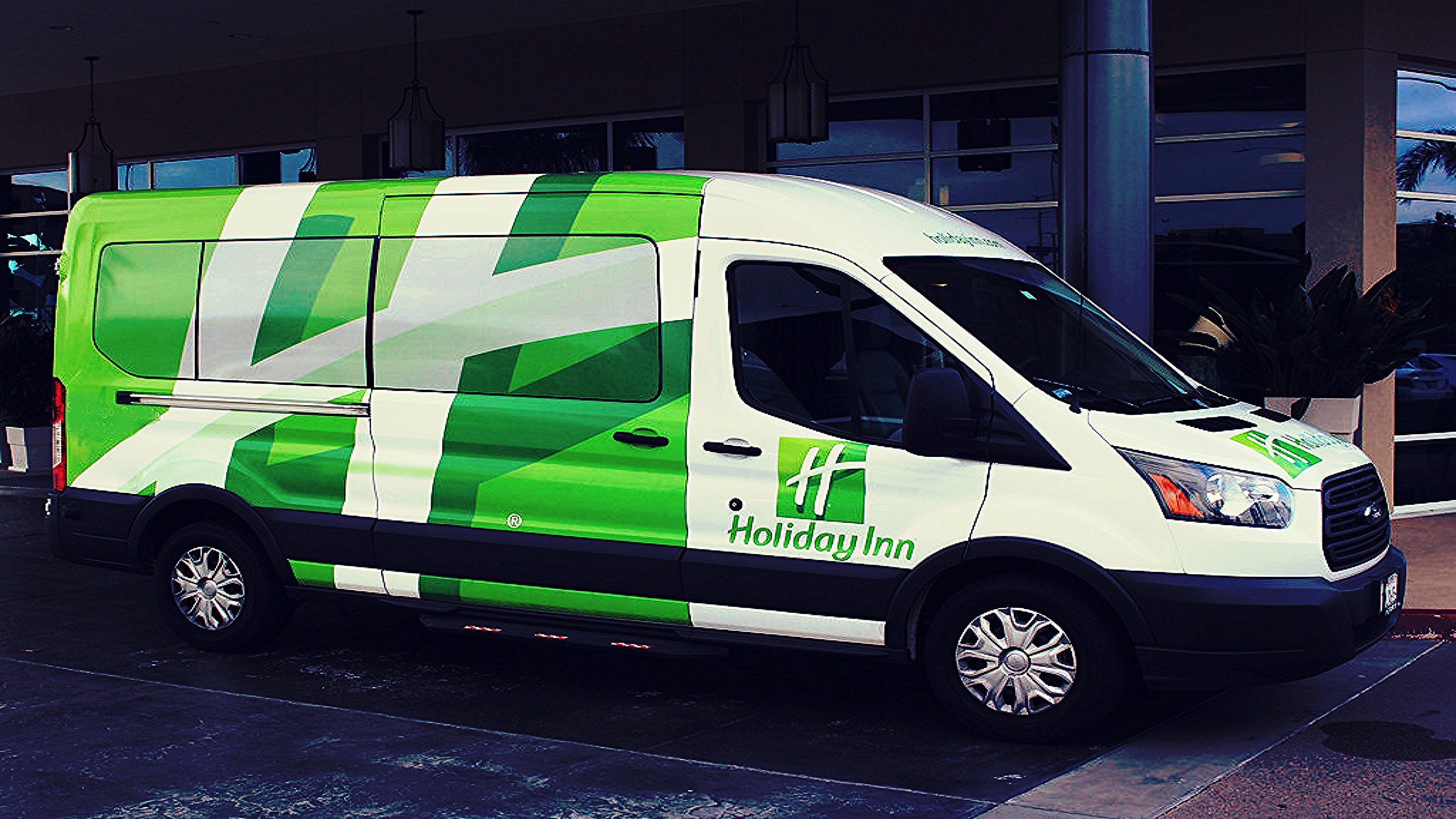 Una camioneta con la marca Holiday Inn estacionada frente a un edificio.