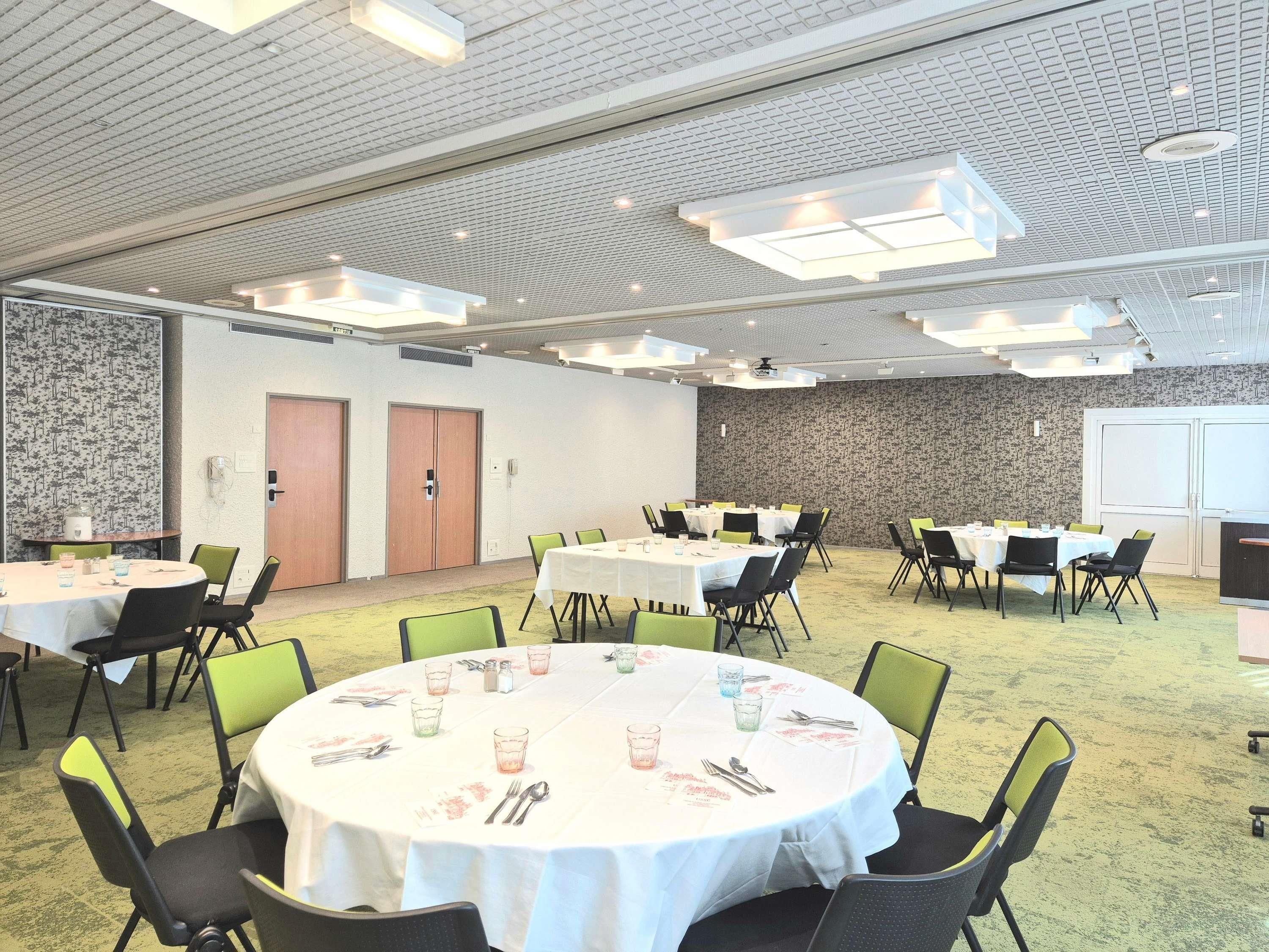 A conference room with round tables, chairs, and a carpeted floor.